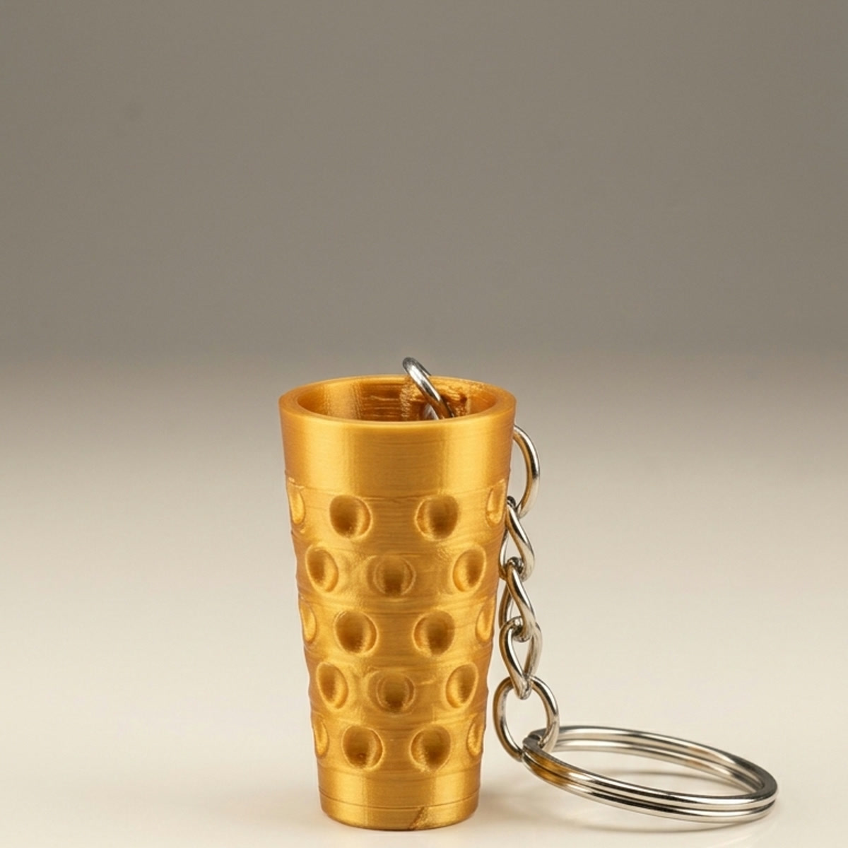 Echte Produktaufnahme des Dubbeglas-Schlüsselanhängers Gold mit Befestigungsloch im oberen Rand